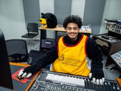 Ethan Garcia wearing part of his Deacon the Bear costume at a soundboard.